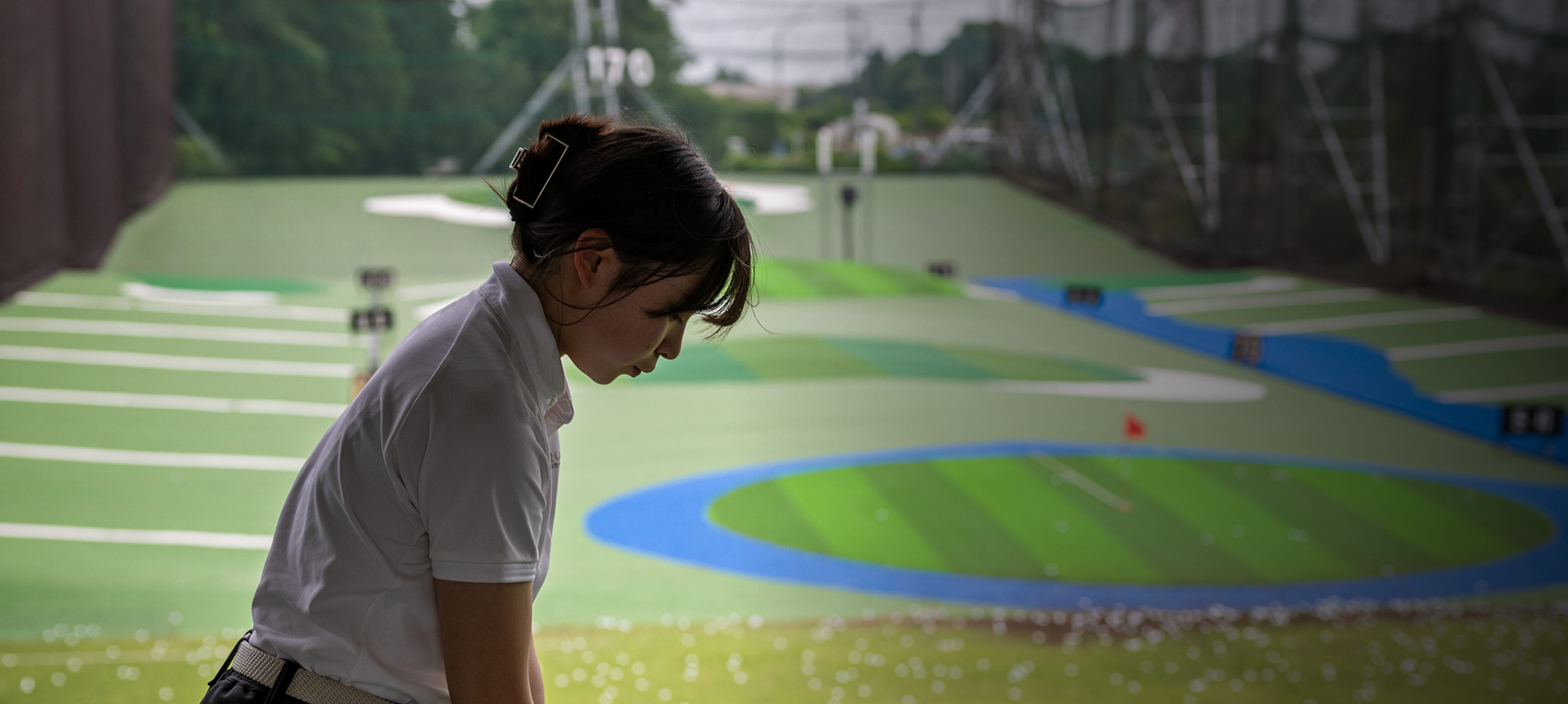 170ヤードのターゲットが見えるゴルフ練習場で打つ人物と散らばるゴルフボール。